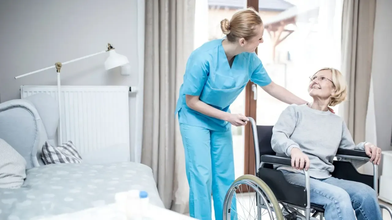 A care home nurse with an elderly lady in a wheelchair