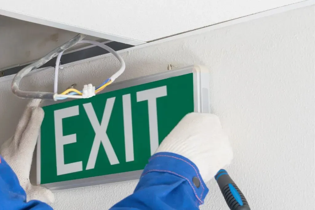 A fire safety engineer installing a new fire exit light up sign