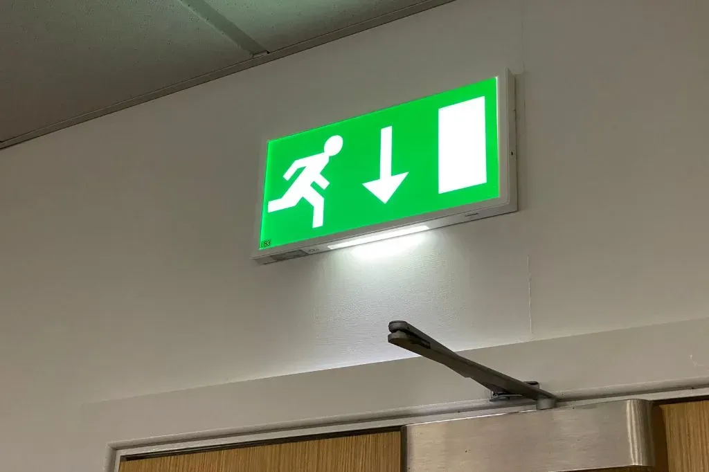 An emergency lighting fire exit sign above an internal fire door
