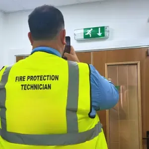 A fire risk assessor photographing a fire exit sign
