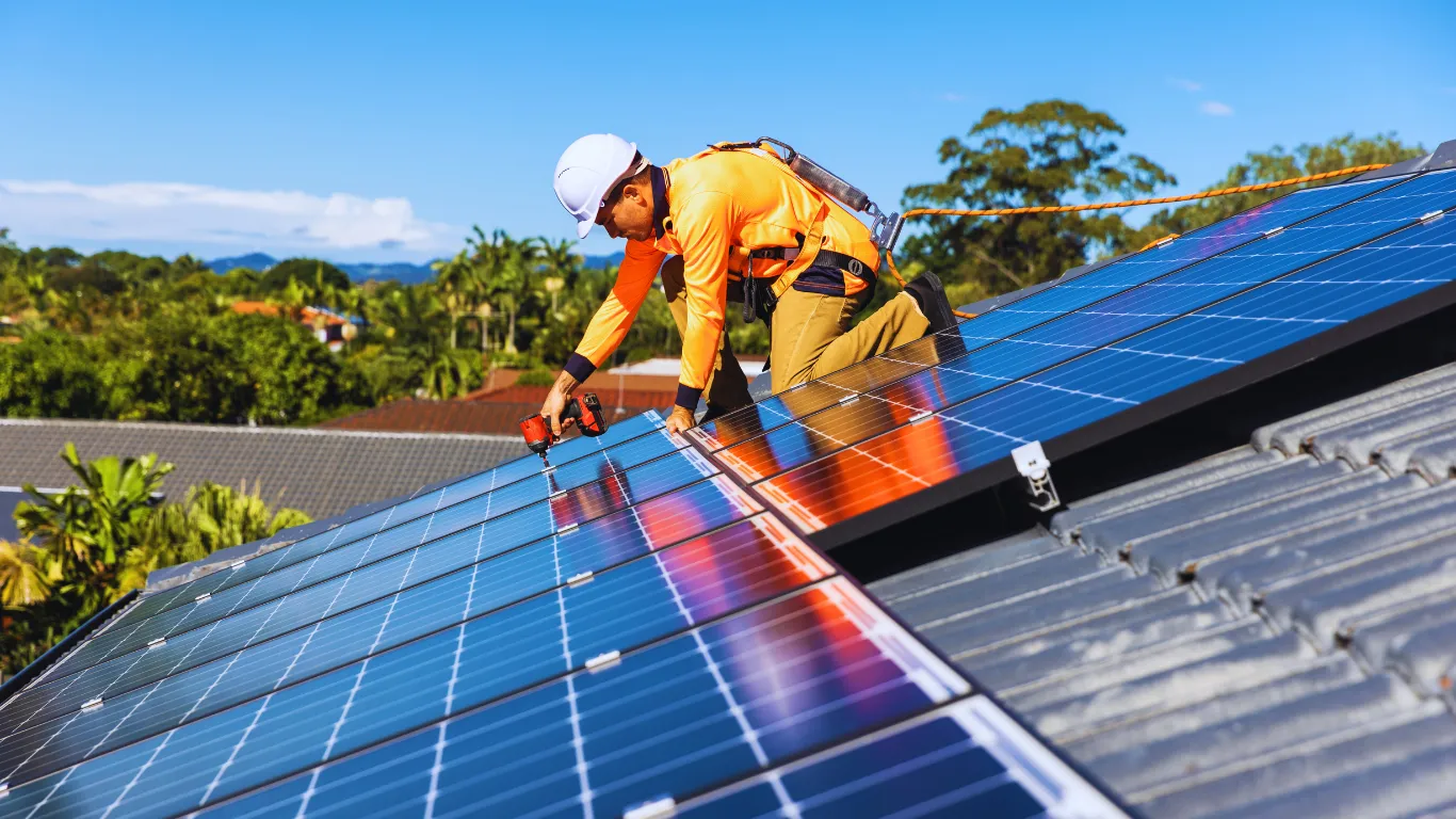 An engineer installing solar panels onto a roof to build sustainable fire safety
