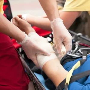 A first aider wrapping an arm in a bandage