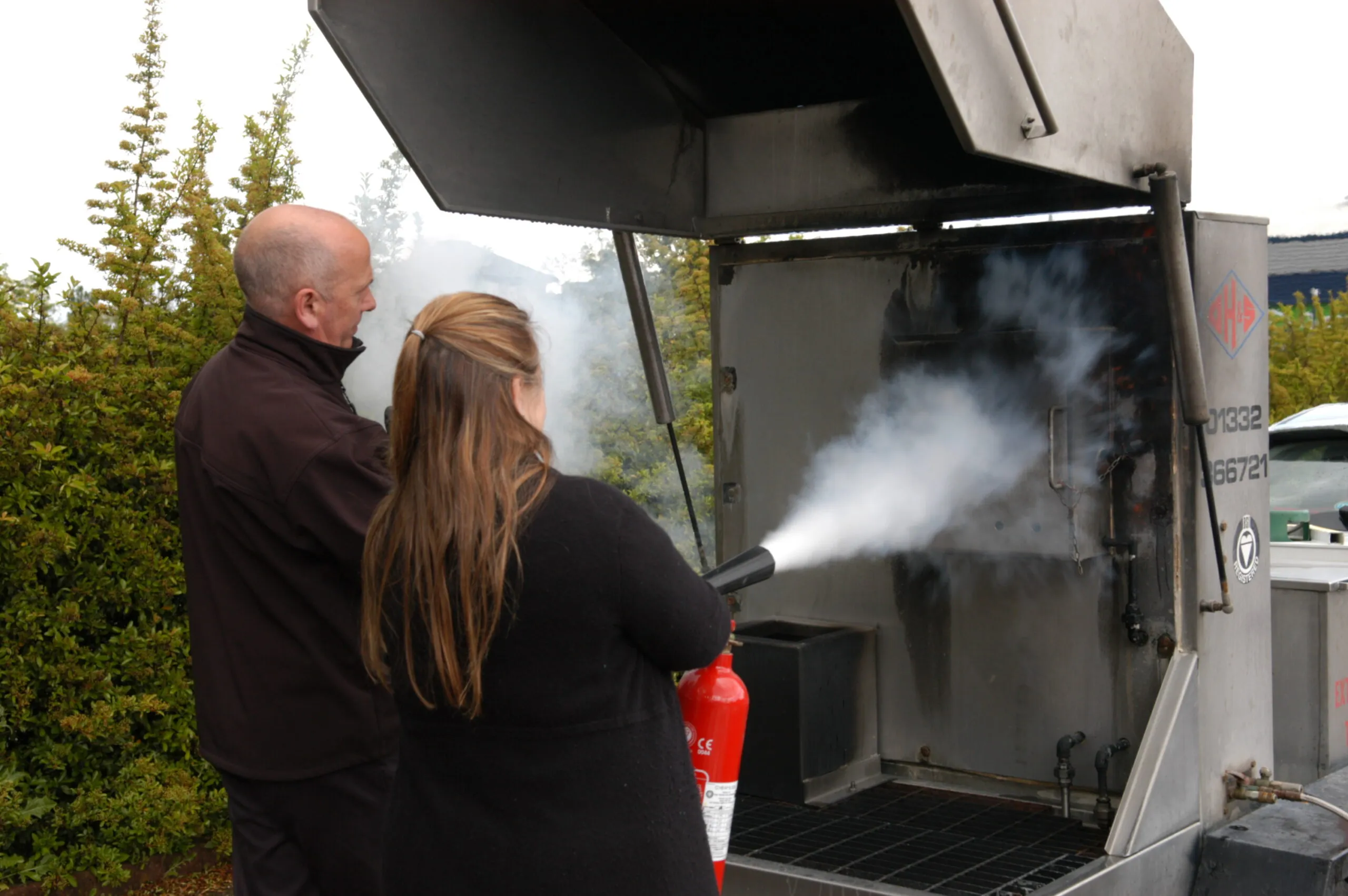 A fire safety expert teaching an office worker how to use a fire extinguisher