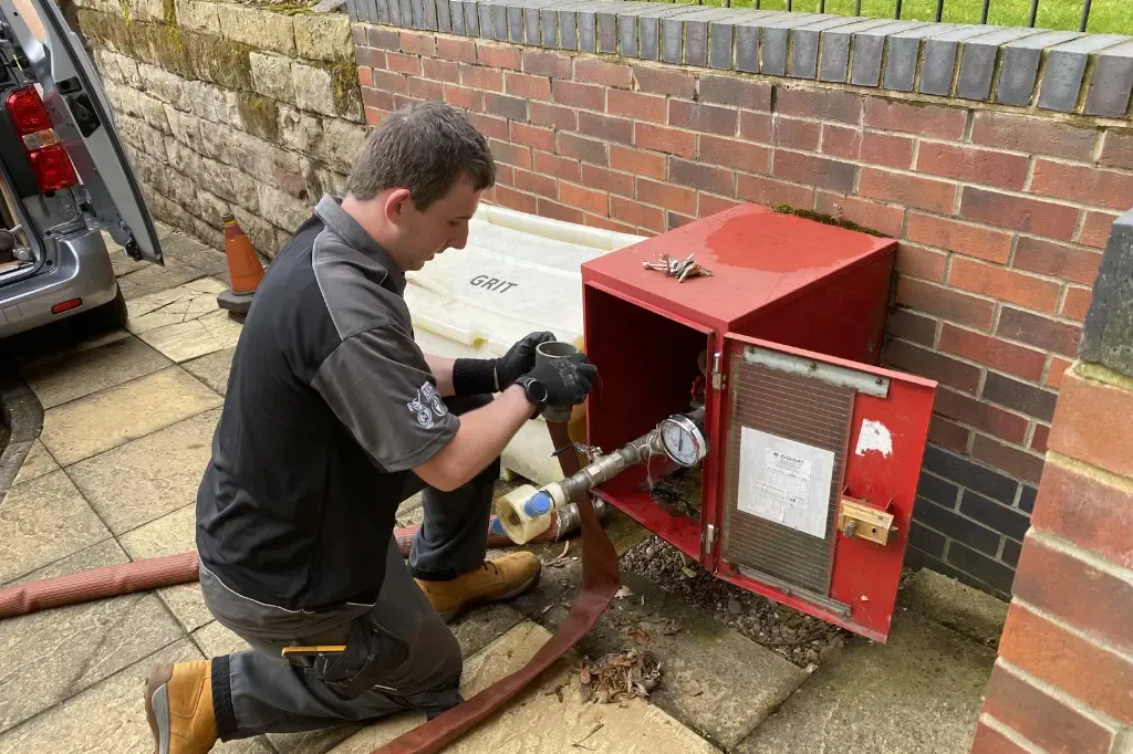 An engineer fitting a hose for a dry riser inlet