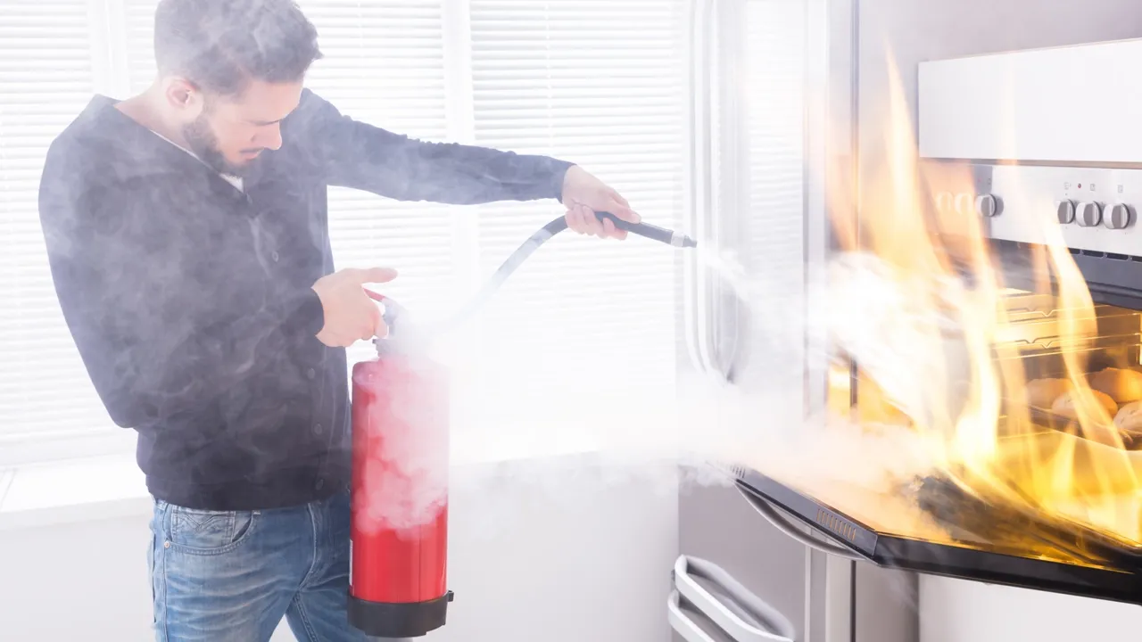 Person using a fire extinguisher in a kitchen