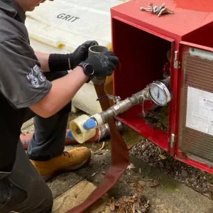 An engineer fitting a hose for a dry riser inlet