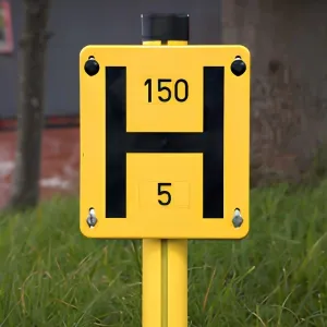 A yellow dry riser sign in grass